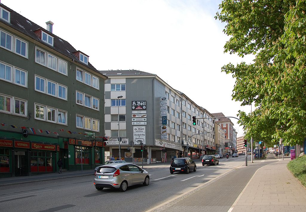 Straße mit fahrenden Autos und Häusern aus den 60er Jahren