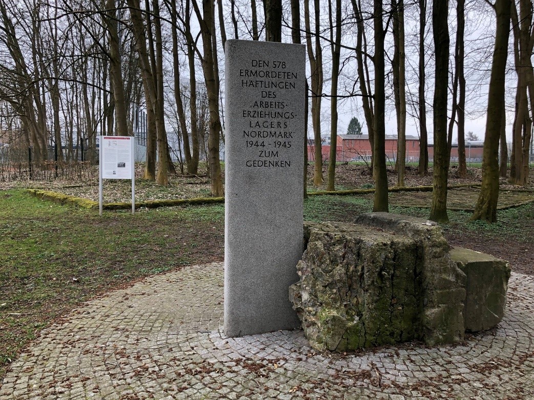 Gedenkstein für die ermordeten Häfltinge im Arbeitserziehungslager Nordmark. Kahle Bäume im Hintergrund