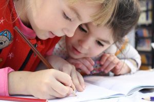 2 Mädchen über ein Buch gebeugt