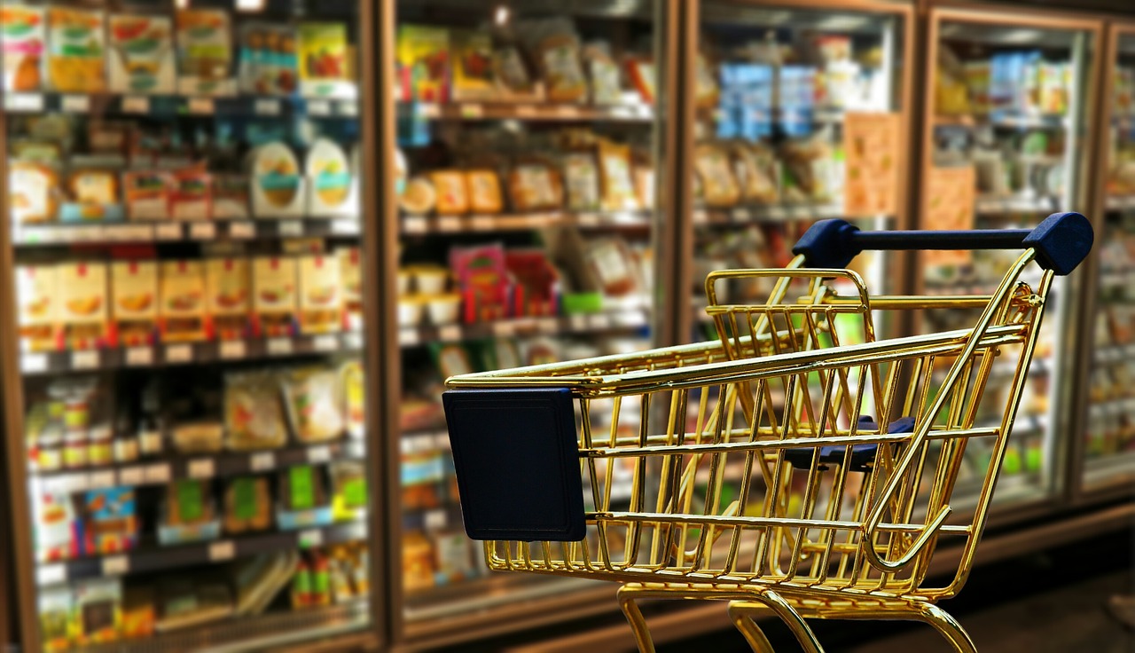 Einkaufswagen vor Kühlregal im Supermarkt