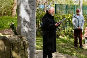 Dieter Heß steht vor dem Gedenkstein und liest etwas vor.