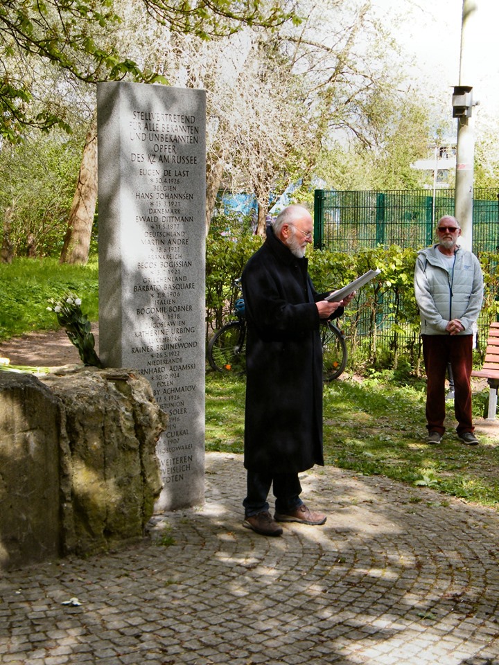 Dieter Heß steht vor dem Gedenkstein und liest etwas vor.