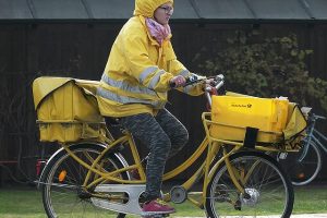 Postzustellerin auf gelben Fahrrad