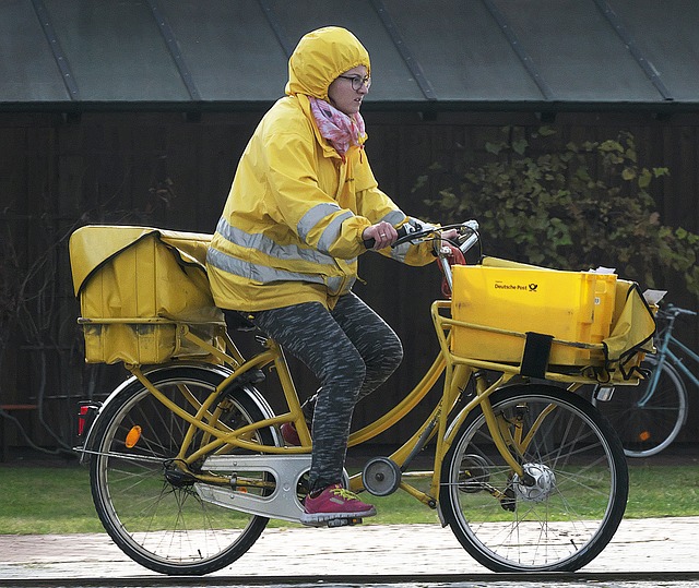 Postzustellerin auf gelben Fahrrad