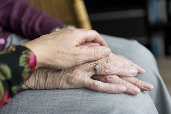 Eine Hand liegt auf der Hand einer älteren Person