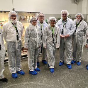 Gruppenbild mit acht Menschen stehen in Schutzanzügen.