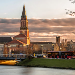Kieler Rathaus in der Abenddämmerung. Bus, Autos und Fußgänger auf der Brücke über den Kleinen Kiel