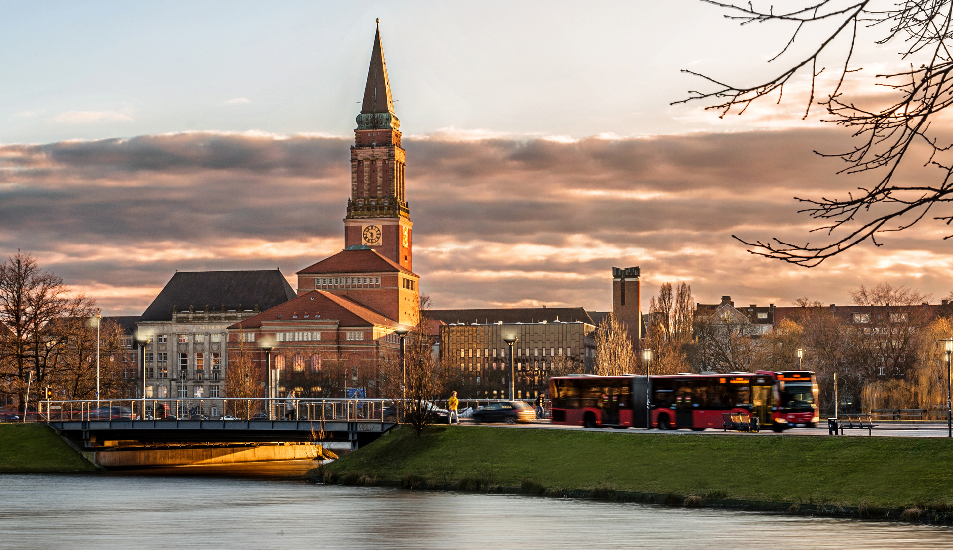 Kieler Rathaus in der Abenddämmerung. Bus, Autos und Fußgänger auf der Brücke über den Kleinen Kiel