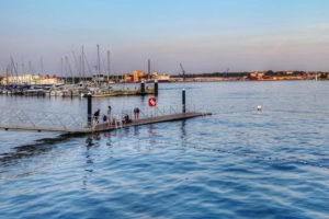 Badesteg an der Kiellinie in den frühen sommerlichen Abendstunden. Im Hintergrund Segelboote, StenaLine und Ostufer