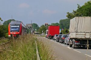 Zug auf einem Gleis neben einer Straße mit Autos im Stau