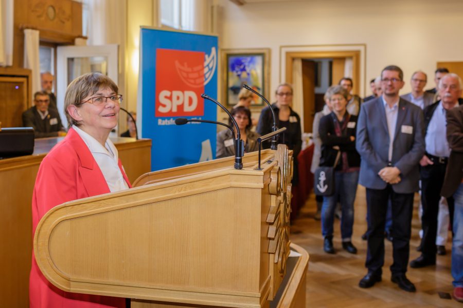 Gundula Raupach im Raatssaal mit Rollup der SPD-Ratsfraktion im Hintergrund