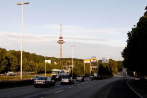 Autos fahren auf einer Bundesstraße mit dem Kieler Fernsehturm im Hintergund