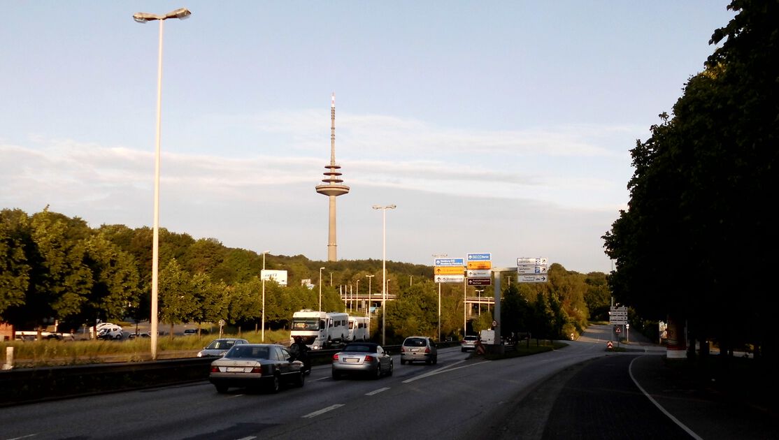 Autos fahren auf einer Bundesstraße mit dem Kieler Fernsehturm im Hintergund