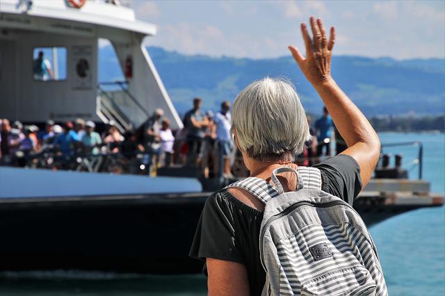 Frau mit grauen Haaren winkt Passagieren auf einer Fähre zu