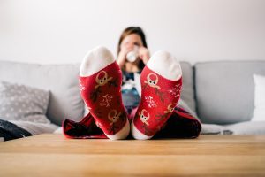 Eine Frau sitzt auf dem Sofa und streckt ihre Füße in roten Wintersocken auf einem Couchtisch aus