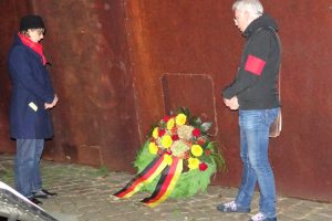 Ein Mann und eine Frau stehen links und rechts von einem Kranz