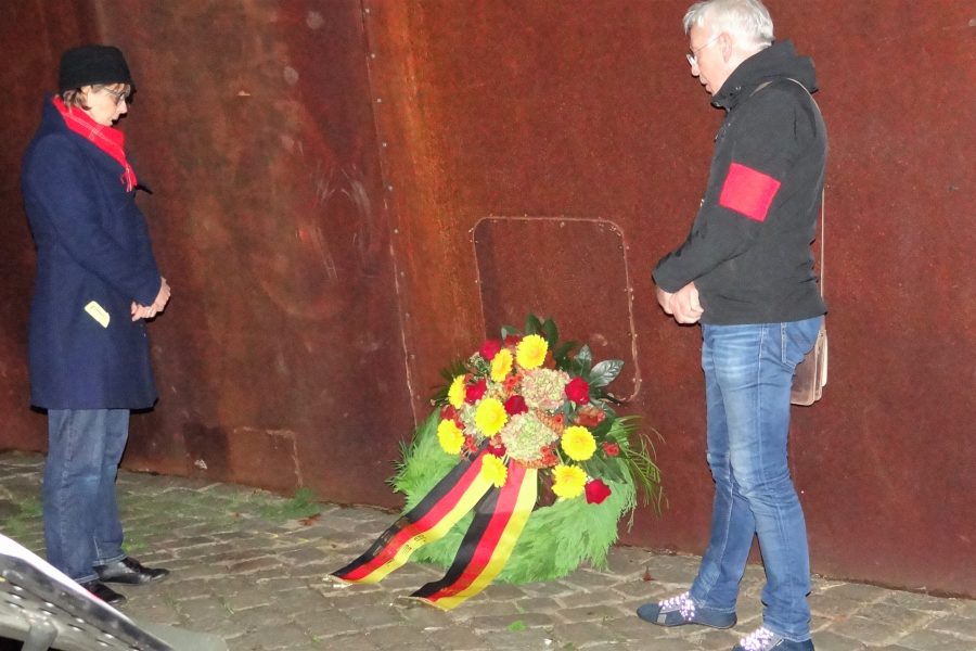 Ein Mann und eine Frau stehen links und rechts von einem Kranz