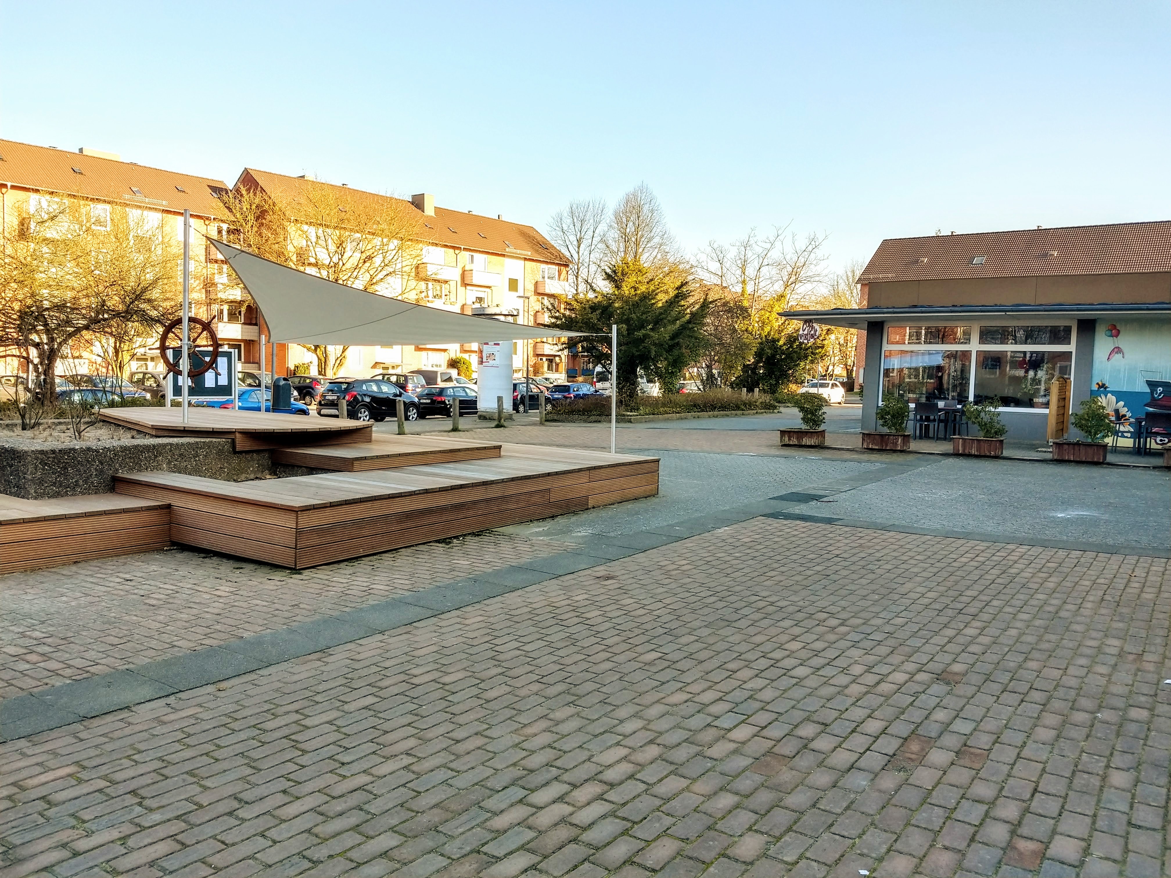 ein von Häusern umstandener Platz mit Kopfsteinpflaster und Holzbänken