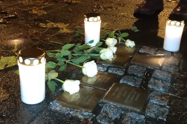 Kerzen und Blumen auf Stolpersteinen